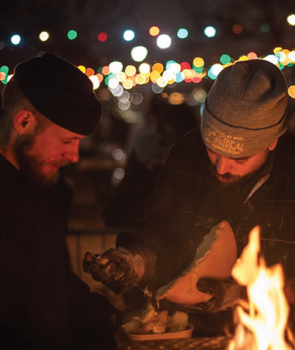 dos hombres comiendo quedo raclette en el festival del mercado navideño atwater